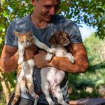 Man holding kitten and puppy
